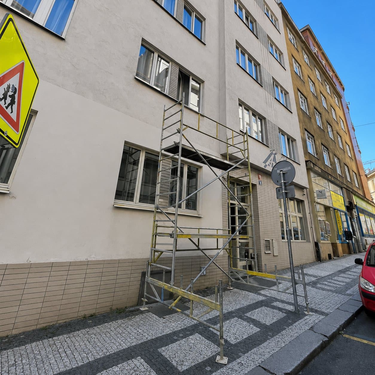 Lešení postavené na chodníku před fasádou hotelu při montáži banneru